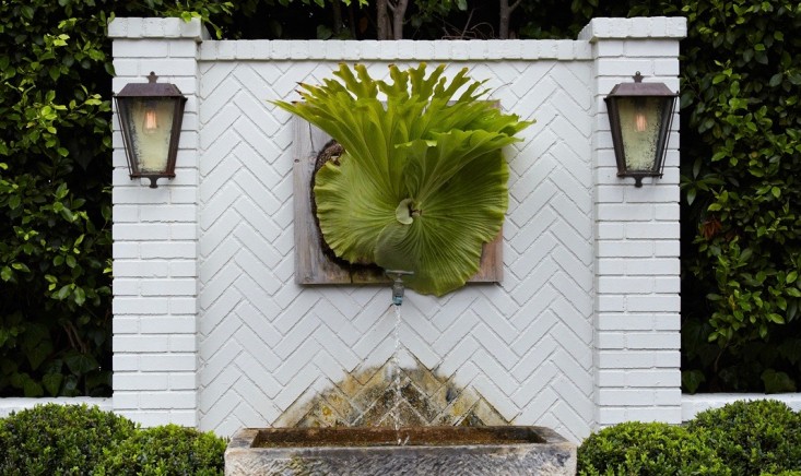 wall-lanterns-wall-fountain-shrubs-white-brick-staghorn-fern-succulents-herringbone-gardenista-1 (1)